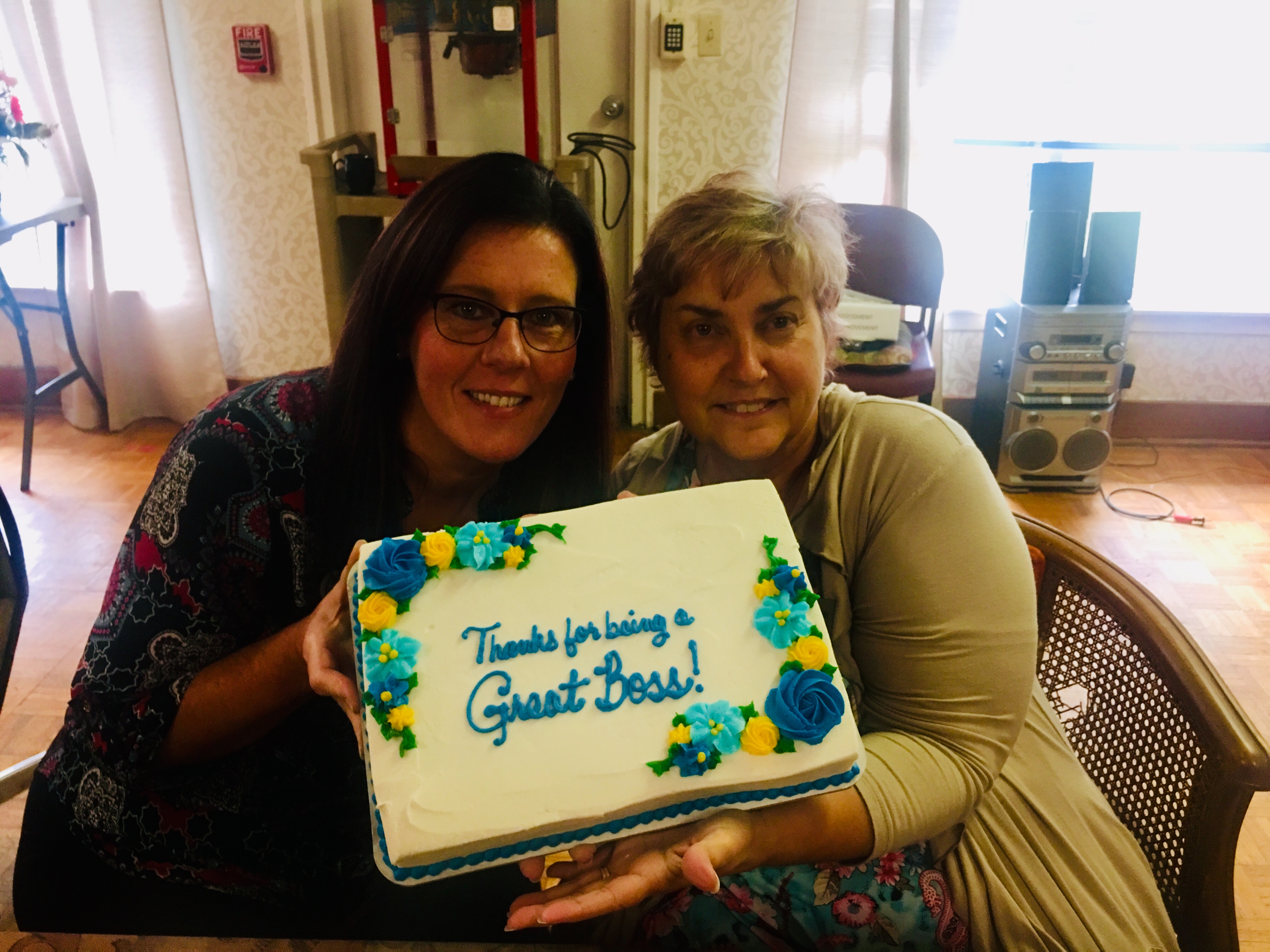 Staff members holding up a cake that says thanks for being a great boss!